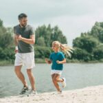 A father and a daughter in a sporty outfit, happily running together