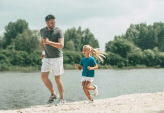 A father and a daughter in a sporty outfit, happily running together