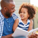 A father and his daugther happily reading a book together