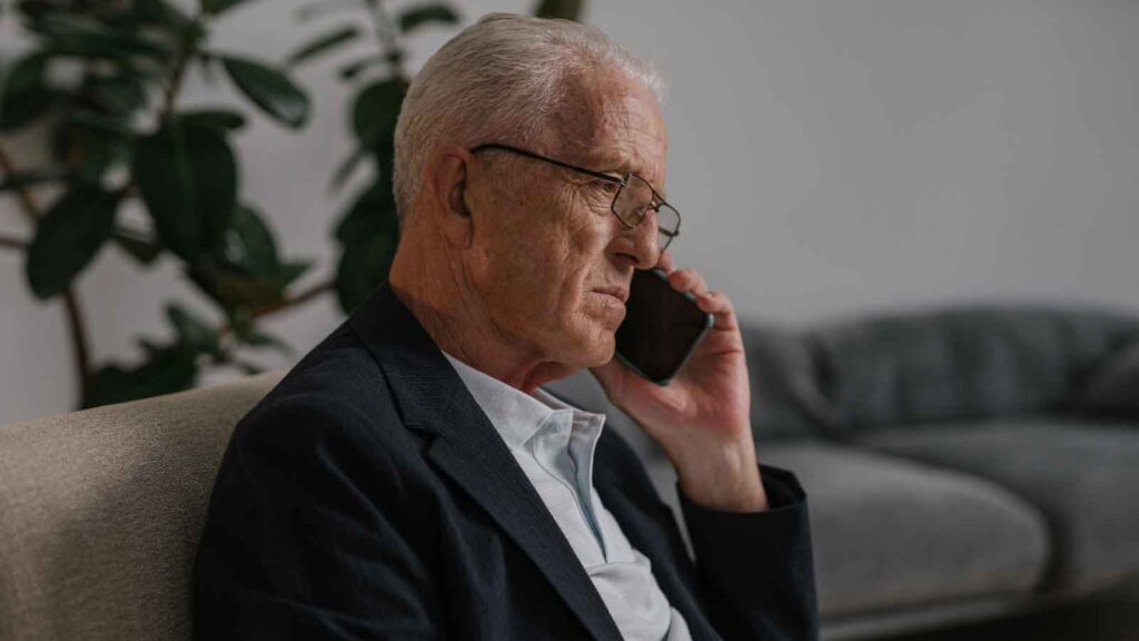 Elderly man sitting and speaking on the phone.