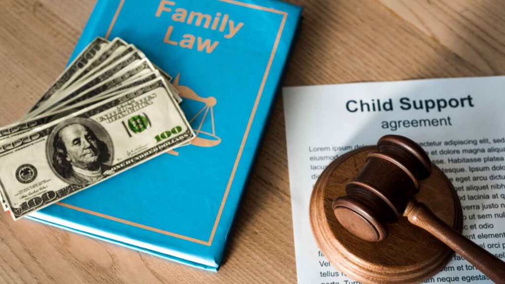 Family law documents, child support books, money, and a gavel on a desk