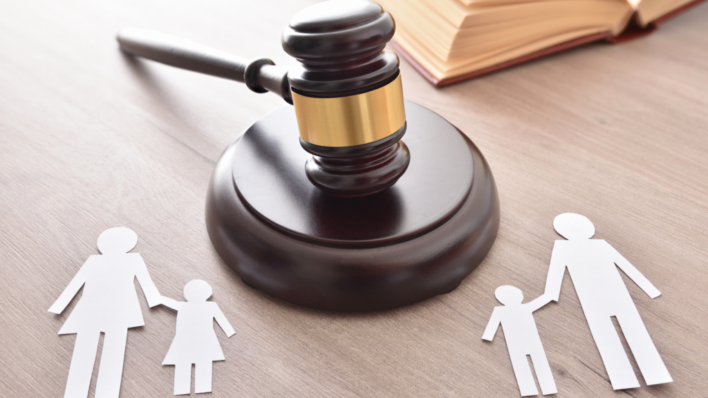 Wooden gavel on table beside paper cutout figures representing family