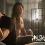 Man and woman sitting apart on bed, avoiding eye contact after a fight