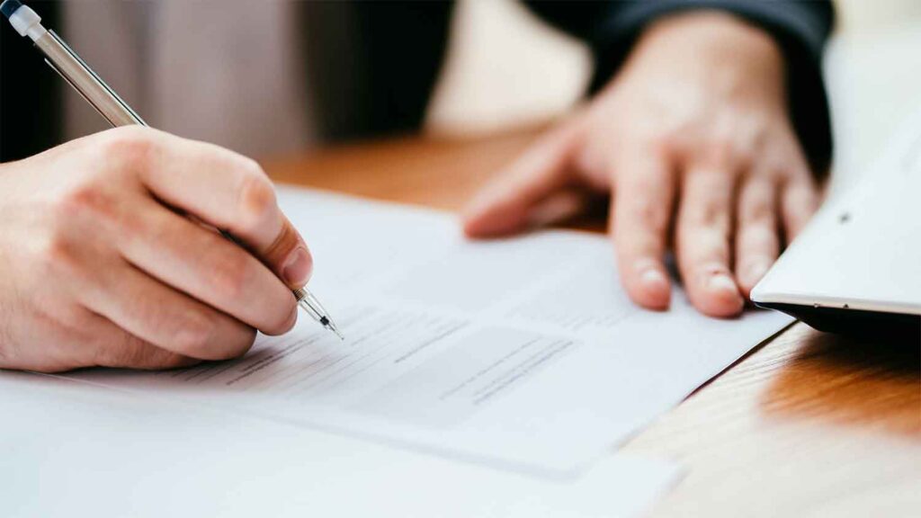 A man filling out important documents at a desk