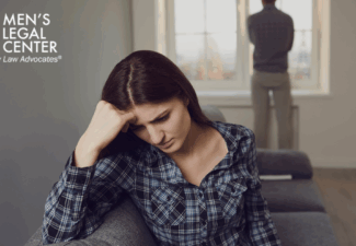 Wife sitting on a sofa while husband stands by the window,