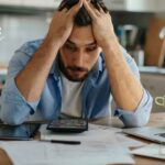 A worried man sitting at a table preparing his finances during divorce