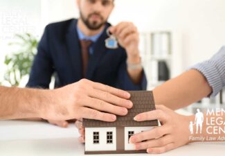 Man and woman each placing a hand on a model house during a legal consultation