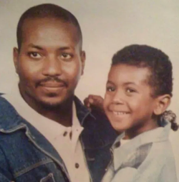 Portrait of a man and a young boy smiling, with the man wearing a denim jacket.
