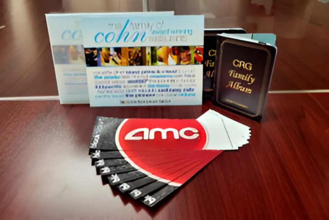 AMC movie tickets fanned out on a wooden table with family album booklets behind.