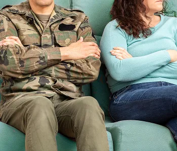 Two people sitting side by side on a green couch, arms crossed, facing away from each other.