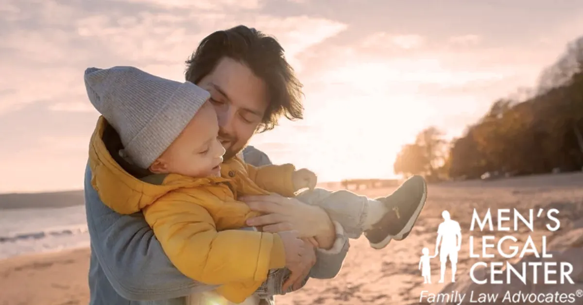 Man holding young child on beach at sunset, with "Men's Legal Center Family Law Advocates" text.