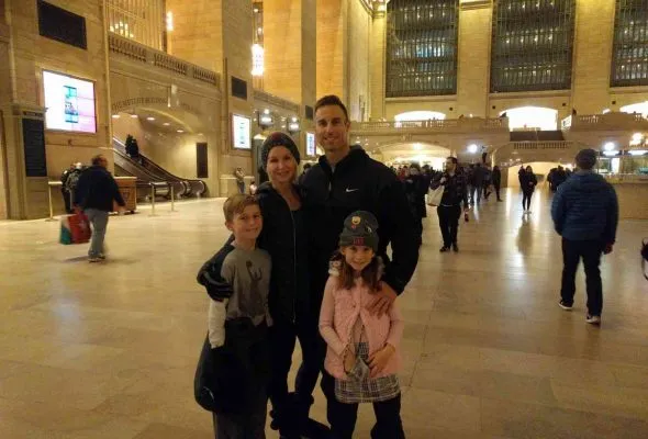 Family of four posing in a large, well-lit indoor public space with high ceilings.