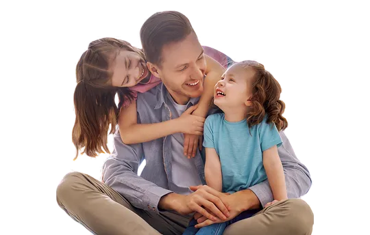 Man sitting cross-legged smiling, embracing two young girls who are laughing.