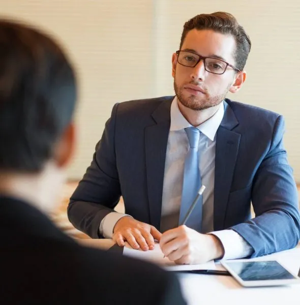 Professional man in a blue suit and glasses attentively listening during a meeting.