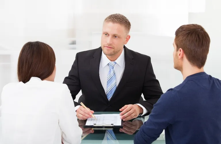 Professional man in suit conducting a meeting with two colleagues at glass table.