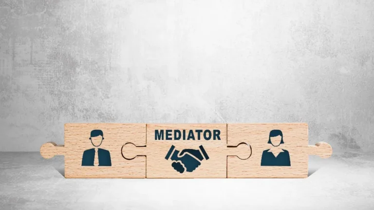 Wooden puzzle pieces with icons of a man, handshake labeled "Mediator," and a woman on a gray background.