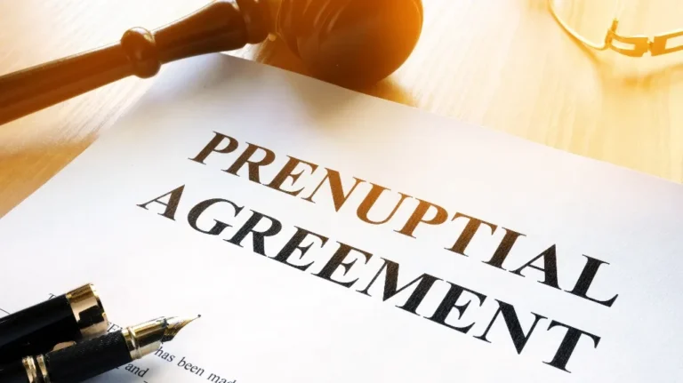 Close-up of a prenuptial agreement document with a fountain pen and wooden gavel on a light wooden surface.