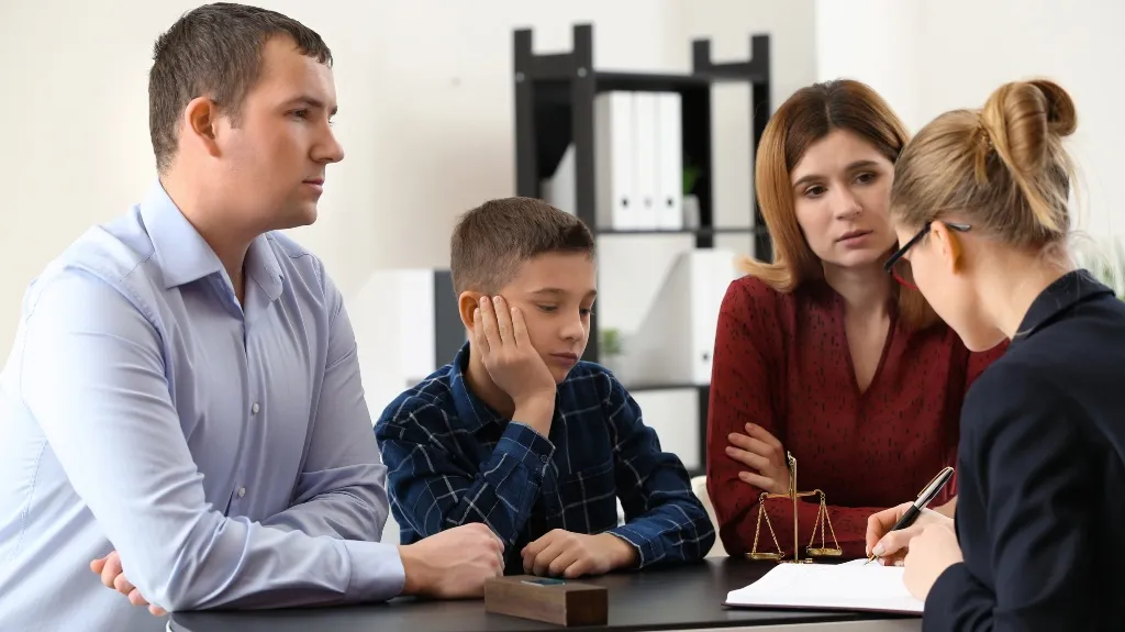 Professional consultation with a man, woman, and boy discussing legal matters with a female advisor.