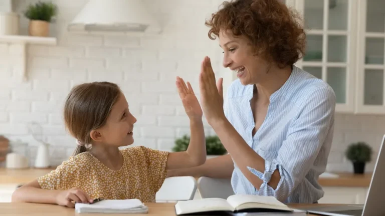 Woman and young girl smiling and giving a high-five in a bright kitchen.