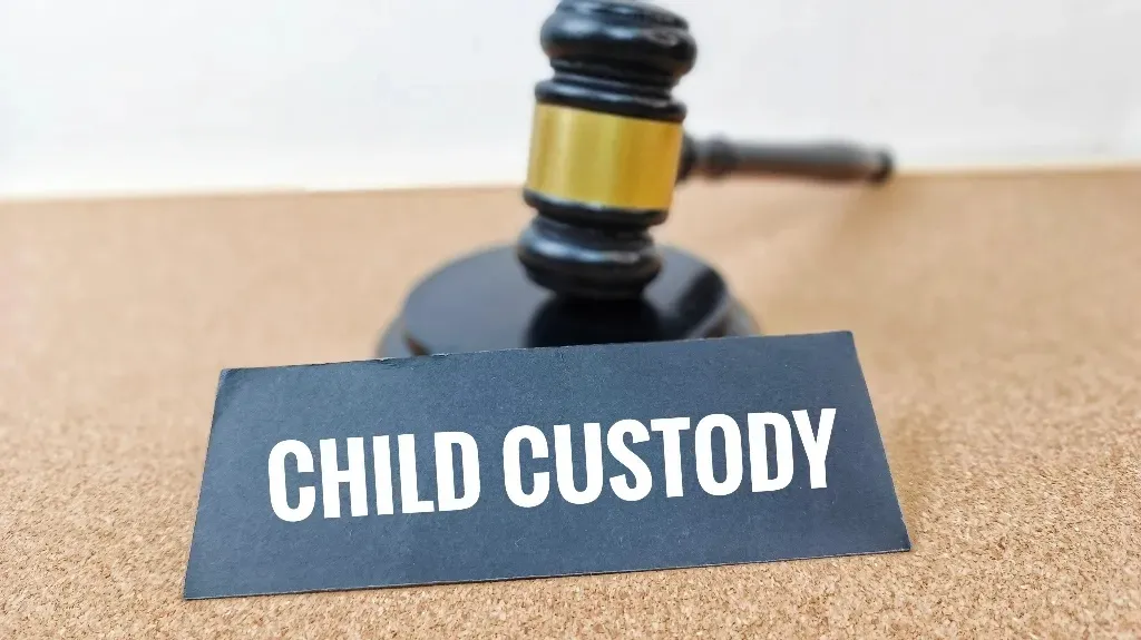 Black gavel with gold band behind a black sign displaying the text "CHILD CUSTODY" in white letters.